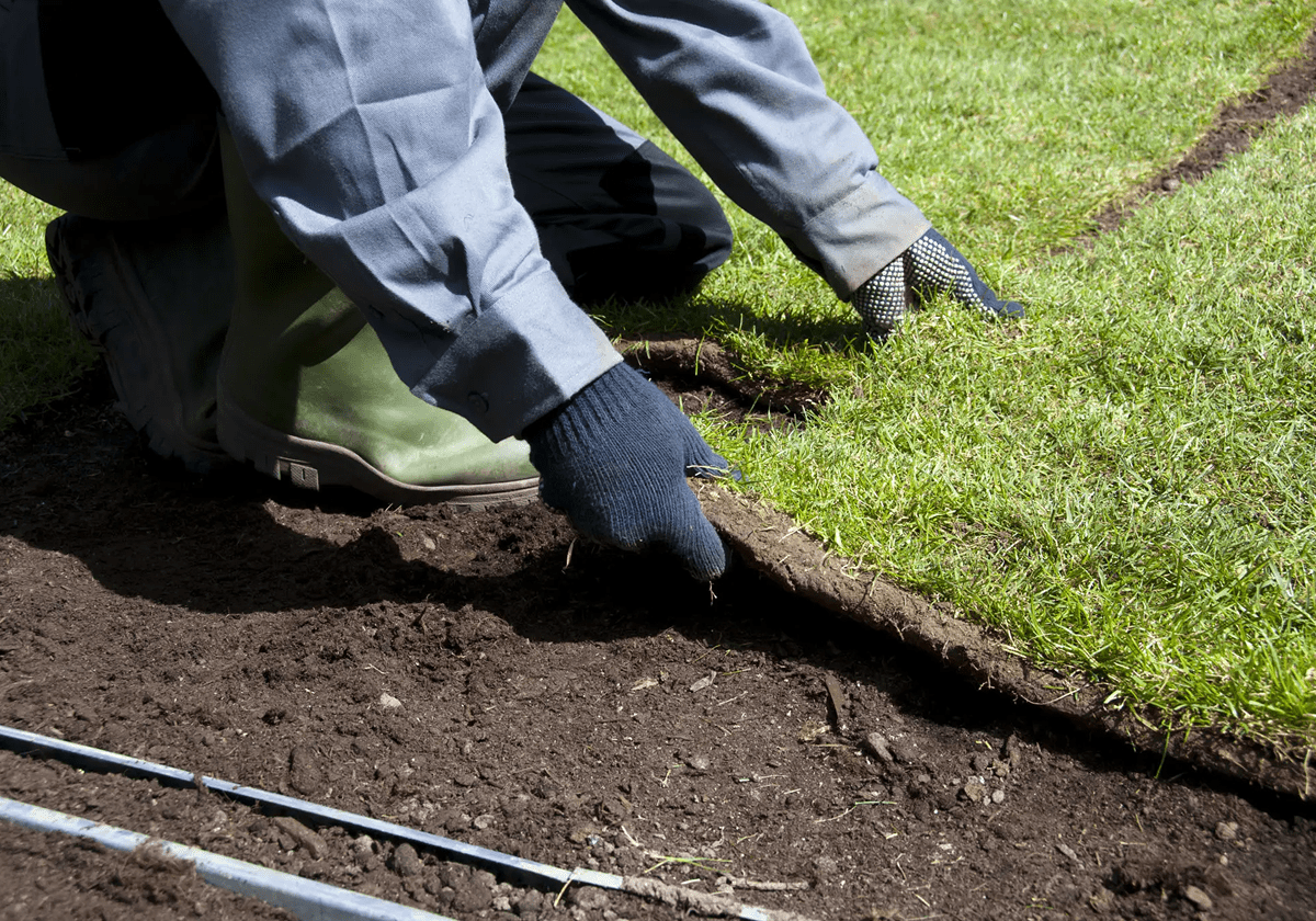 Person laying sod to create a fresh lawn.