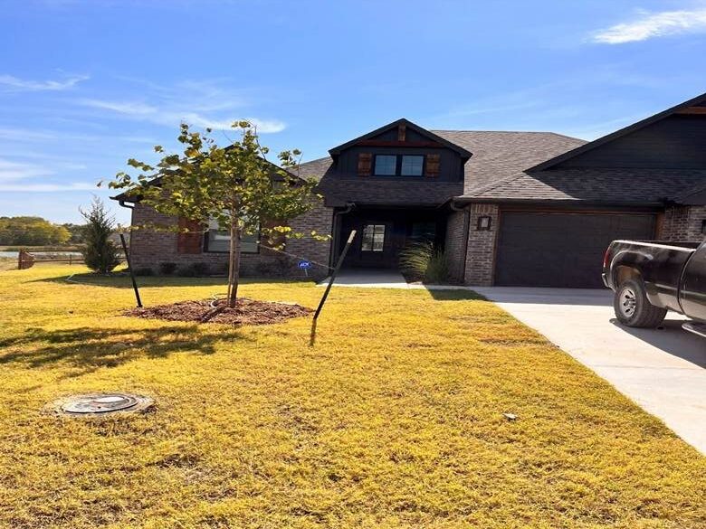 Suburban house with a large lawn and young trees on a sunny day.
